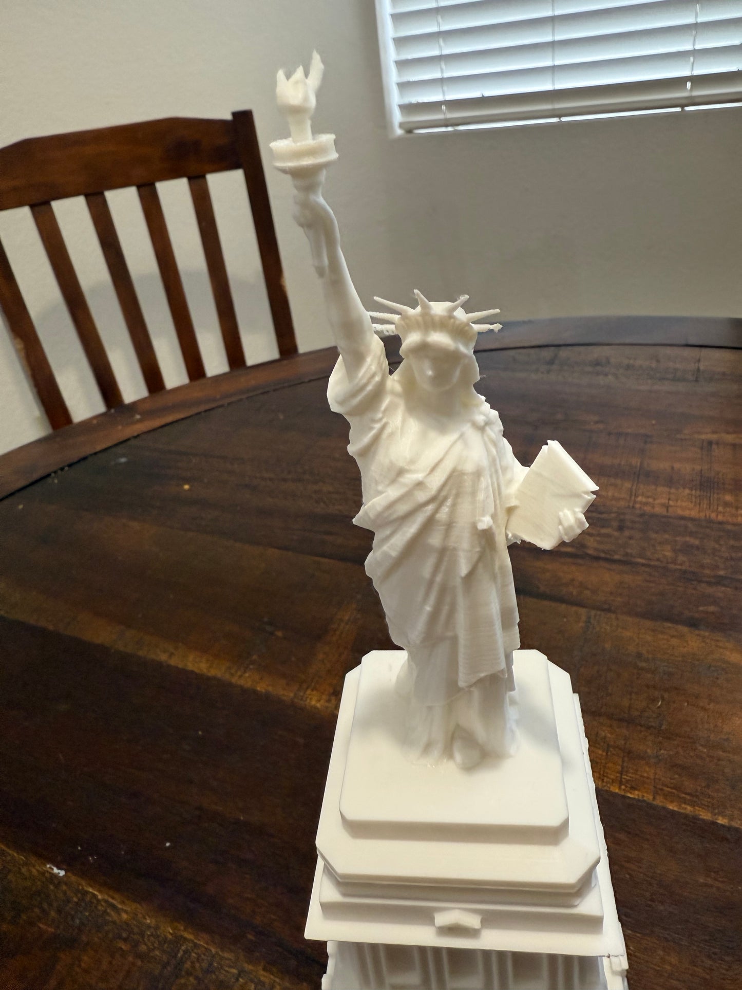Top-down perspective of the white 3D printed Statue of Liberty model focusing on the torch and crown spikes.