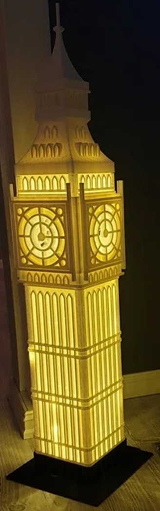Illuminated model of a clock tower with detailed architecture on a dark background